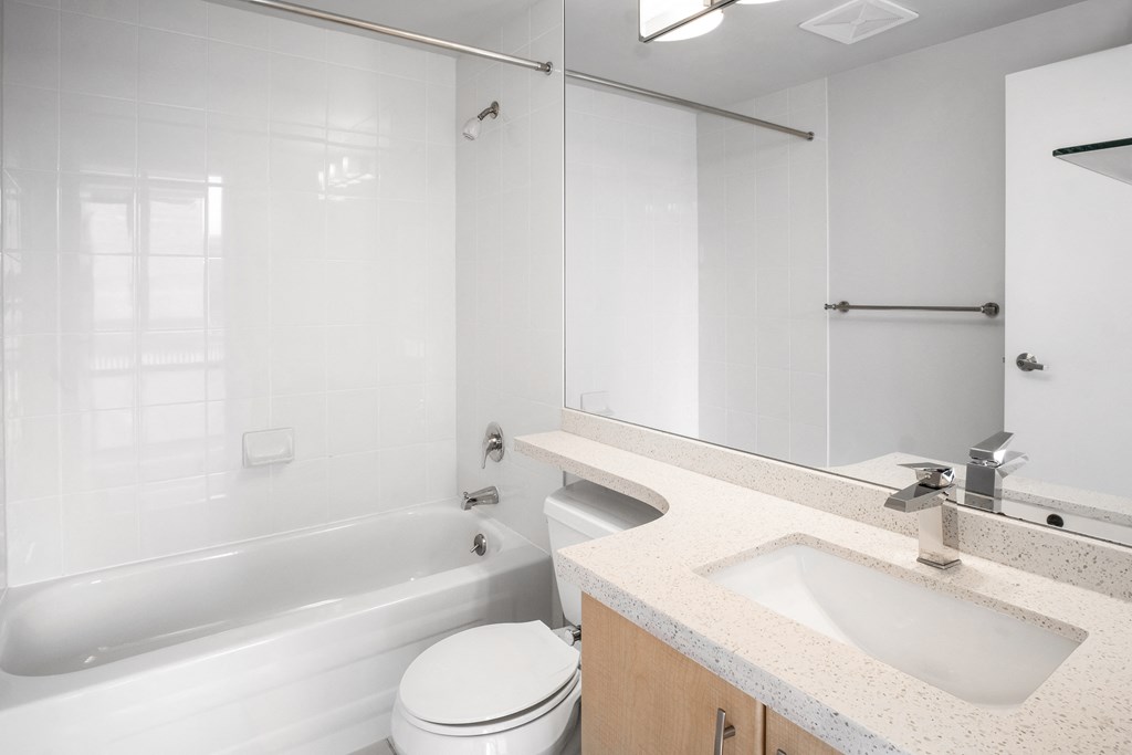 Image of the bathroom in suite 408, which includes quartz countertops, stunning white tile, and chrome fixtures.