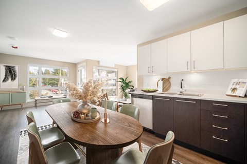 a kitchen and dining room with white cabinets and a wooden table