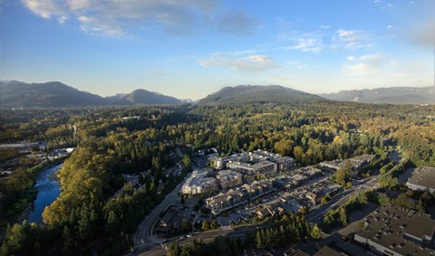 A river flows through a valley with a town and mountains in the background.