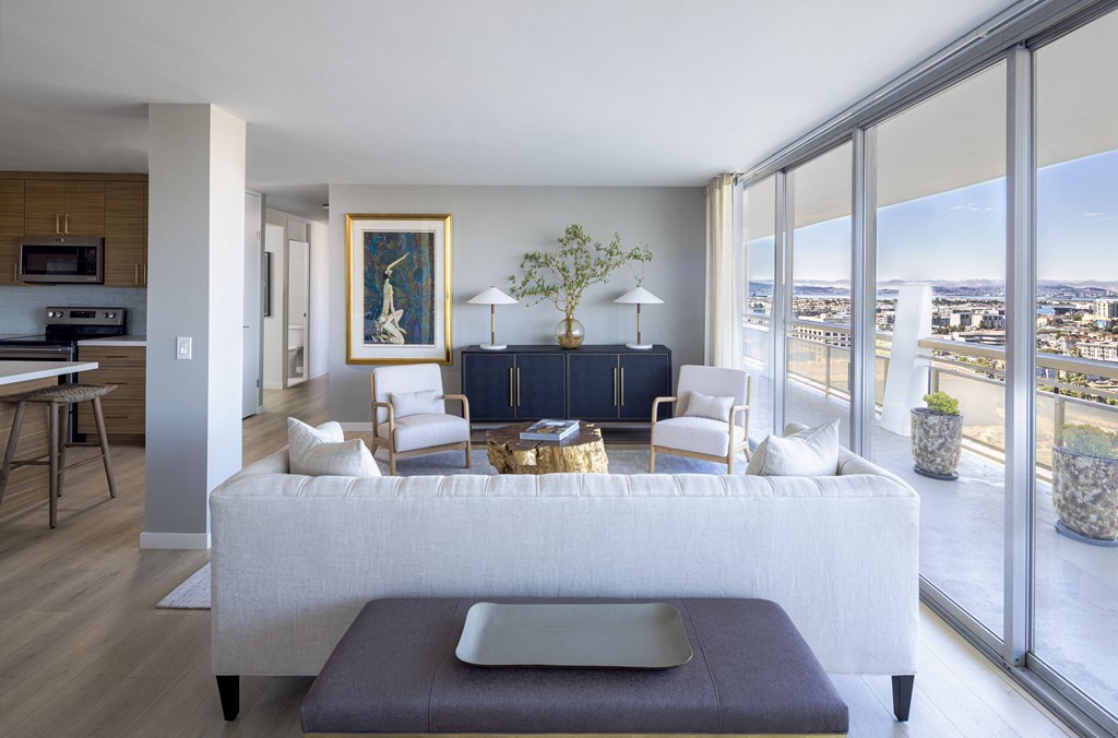 a living room with a white couch and chairs and a view of the city