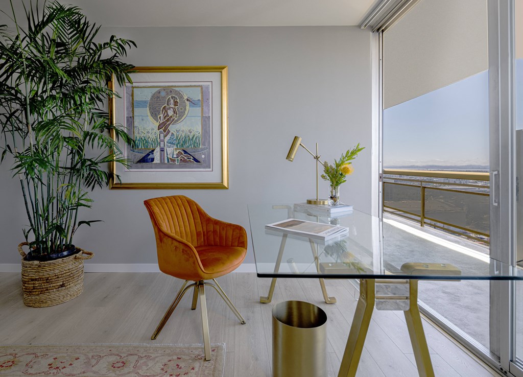 a home office with a glass desk and a view of the ocean