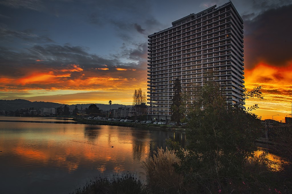 a skyscraper at sunset next to a body of water