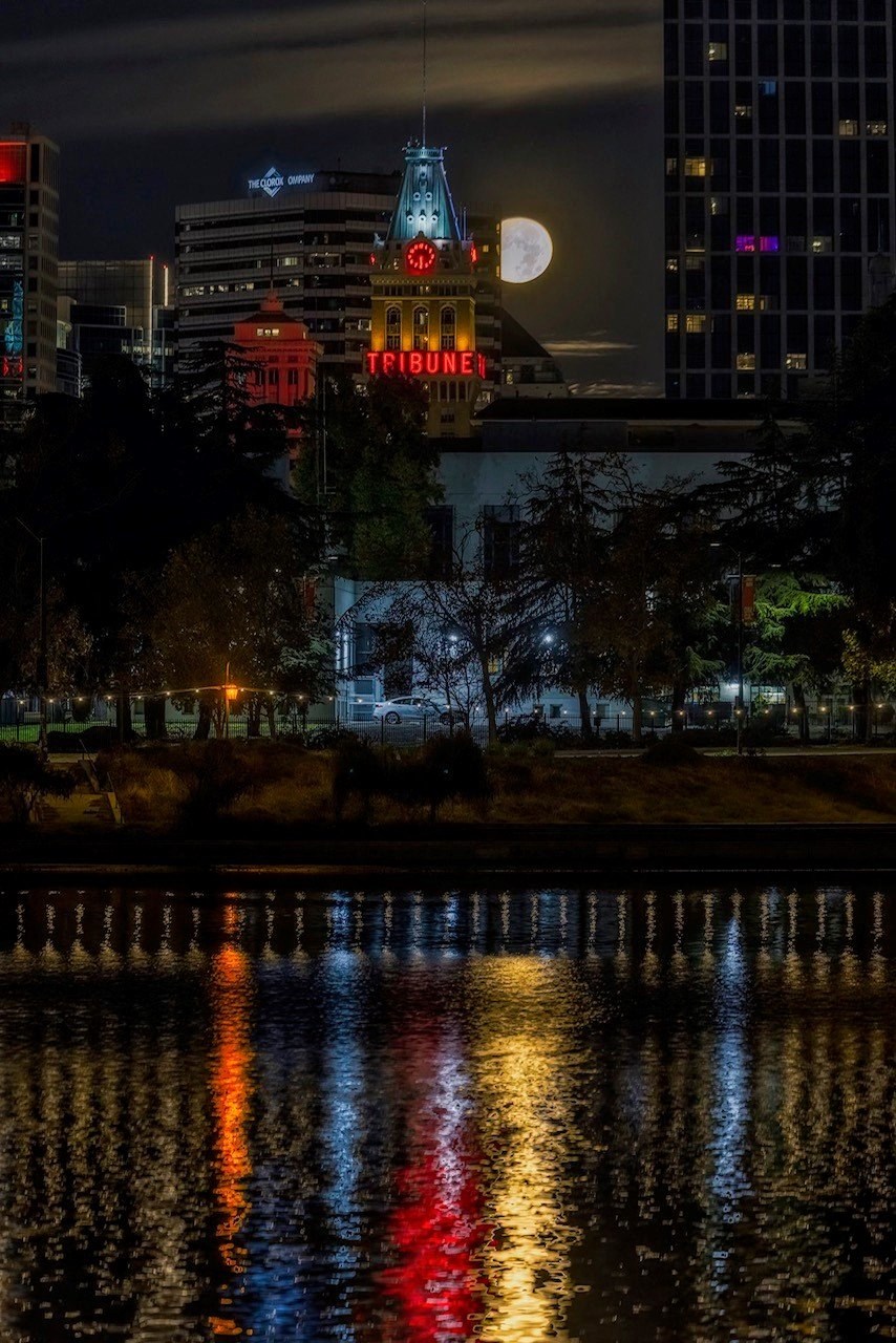 a city at night with the moon over the water