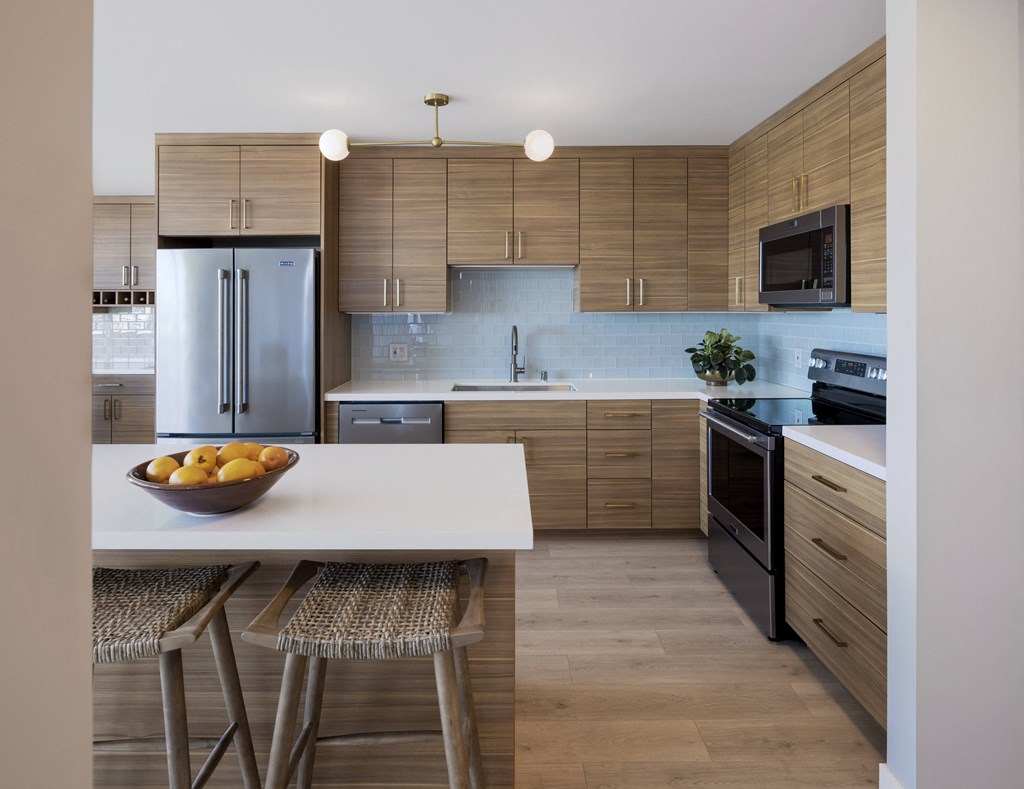 a kitchen with wooden cabinets and a white island with a bowl of fruit