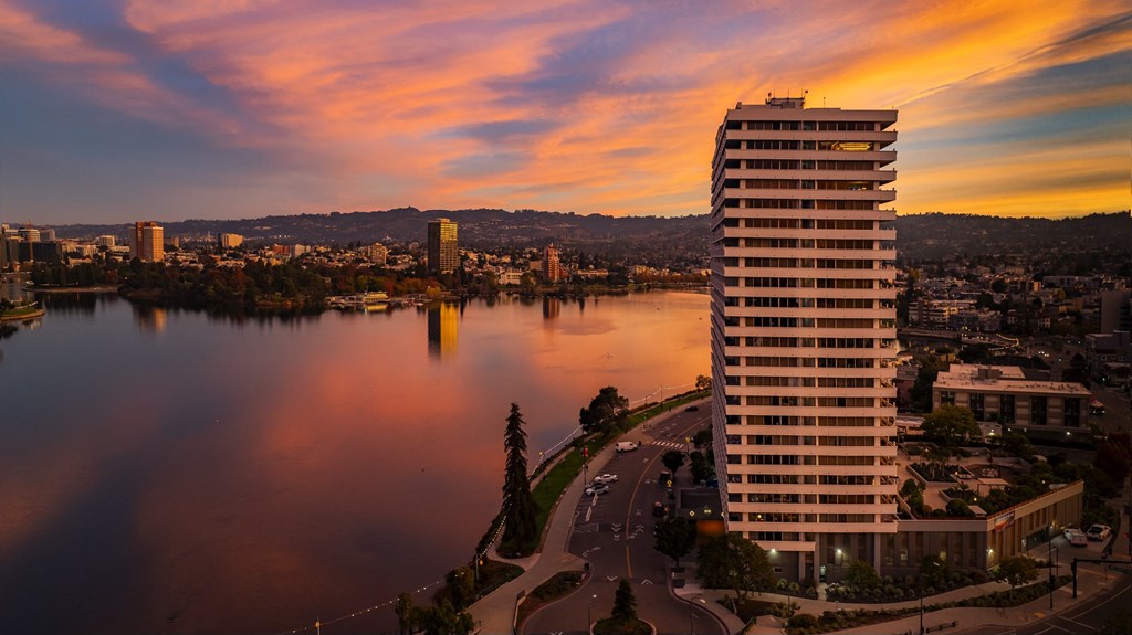 a skyscraper overlooking a lake and a city at sunset