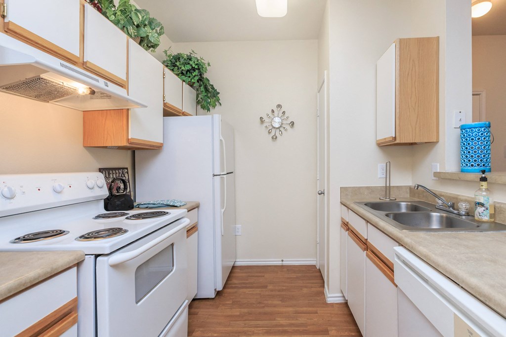 a kitchen with white appliances and wood flooring and a white refrigerator