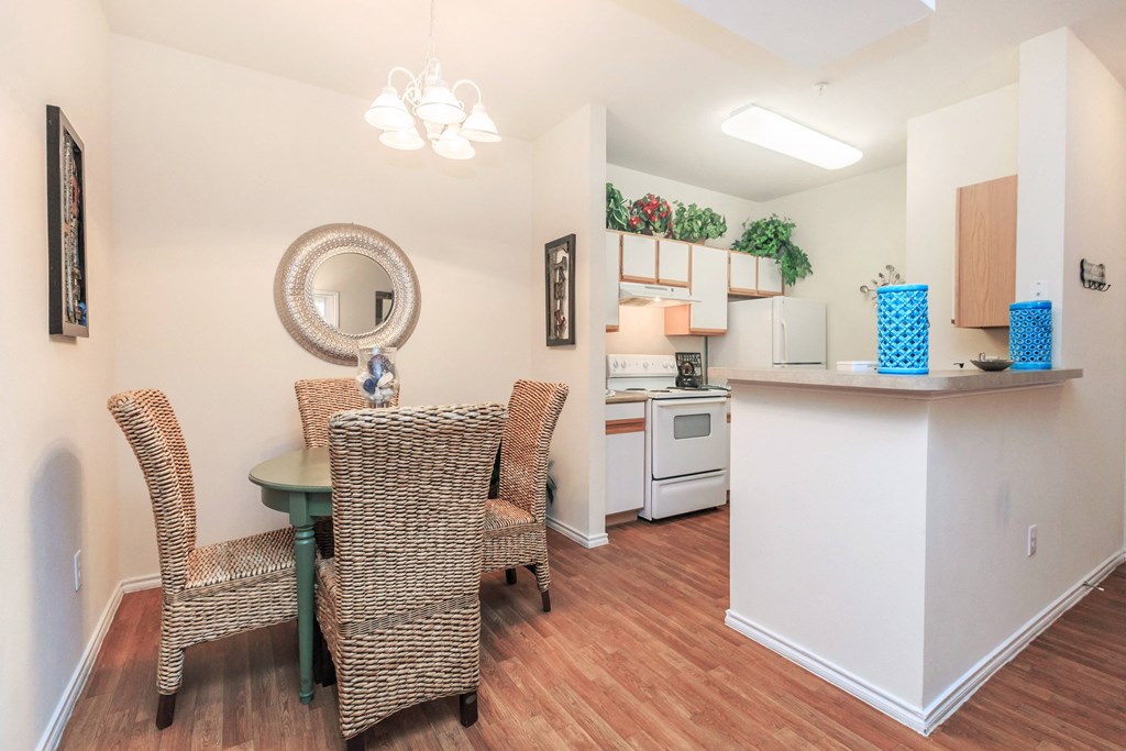 a dining room table with two chairs and a kitchen with a counter