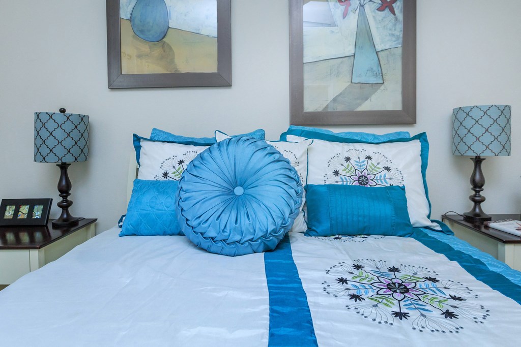 the master bedroom has a large bed with blue pillows and art on the wall