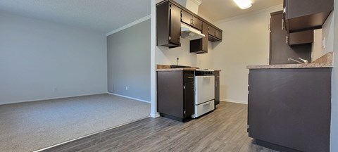 A kitchen area with a white dishwasher and dark brown cabinets.