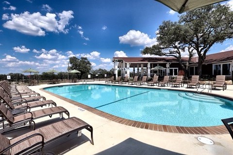 A large outdoor swimming pool surrounded by sun loungers at Vineyard Springs Apartments in Johnson City, TX, 78636