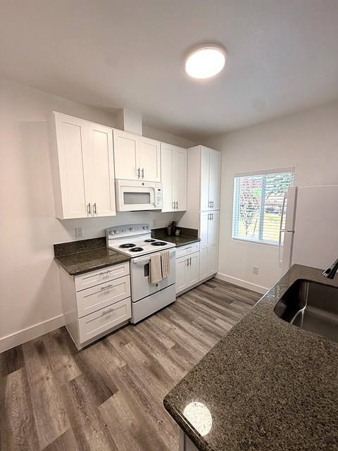 A kitchen with white cabinets and a granite counter.