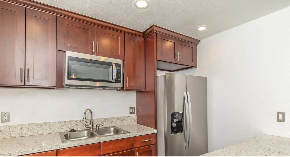 a kitchen with a stainless steel refrigerator and a microwave at Villa La Paz Apartments, Bellflower, CA, 90706