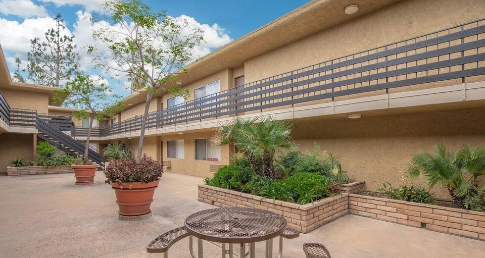 a patio outside of a building with a table and chairs at Villa La Paz Apartments, Bellflower
