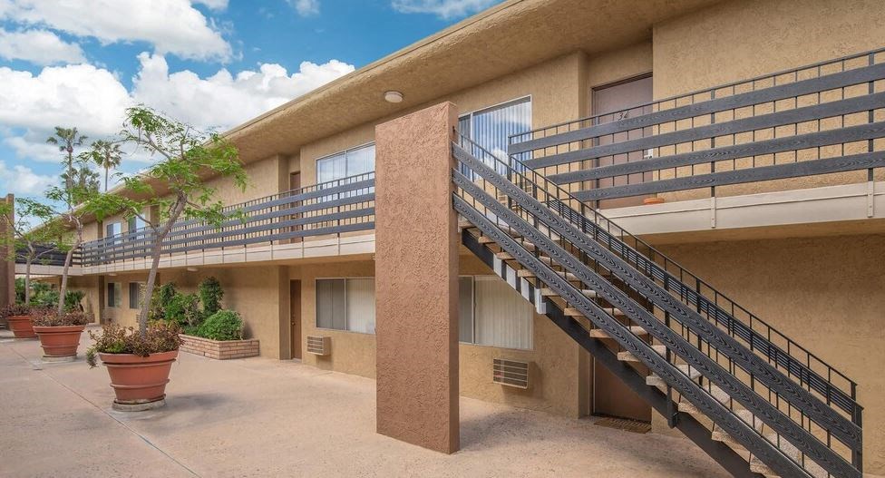 a building with a staircase and a balcony with potted plants at Villa La Paz Apartments, Bellflower, 90706