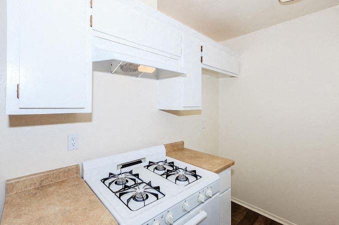 a kitchen with a stove and white cabinets at Villa La Paz Apartments, Bellflower