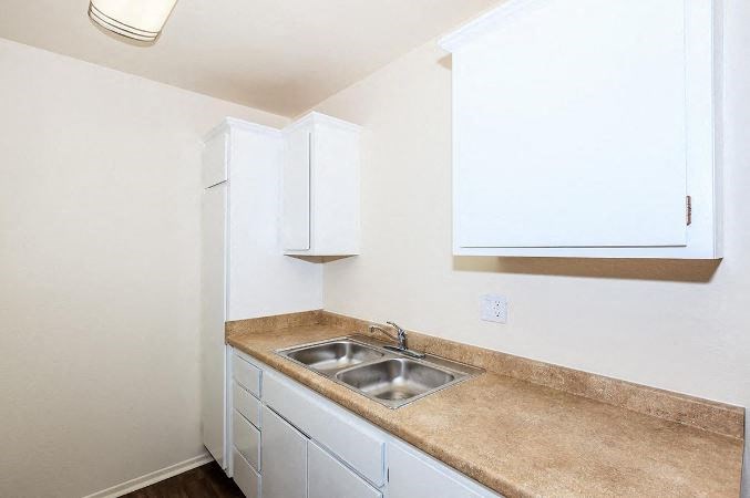 a kitchen with a sink and white cabinets at Villa La Paz Apartments, Bellflower, 90706