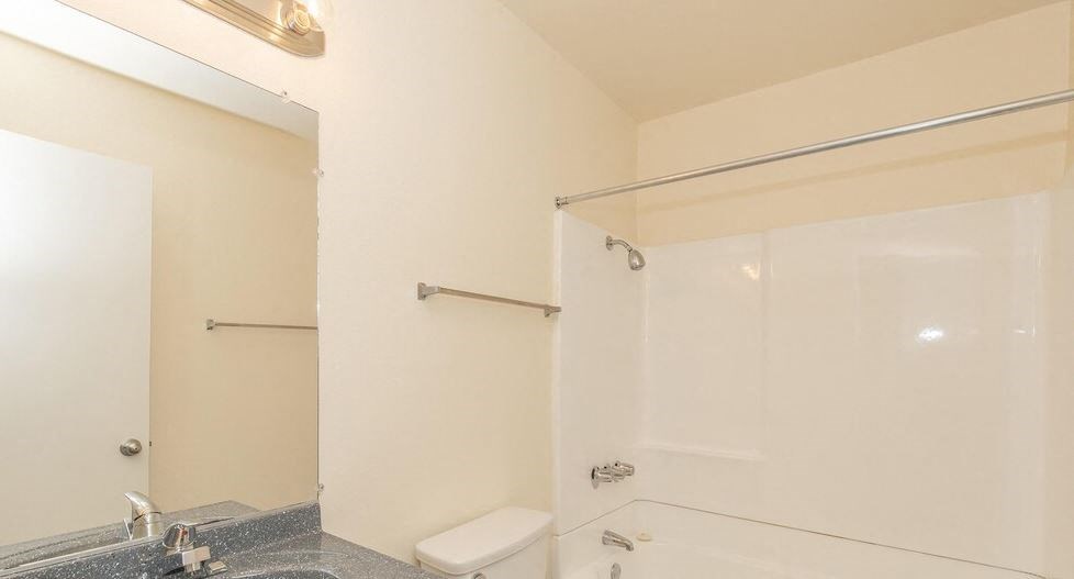 a white bathroom with a shower and a toilet at Villa La Paz Apartments, Bellflower, CA