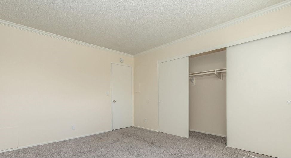 an empty bedroom with a closet and a door to the wardrobe at Villa La Paz Apartments, Bellflower, CA, 90706