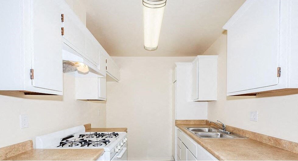 a white kitchen with a stove and a sink at Villa La Paz Apartments, California