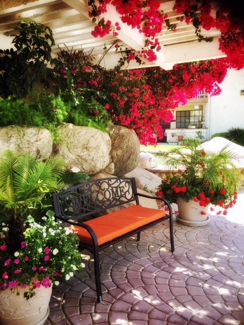 a bench on a patio with flowers and plants at Victoria Springs, Riverside, 92504