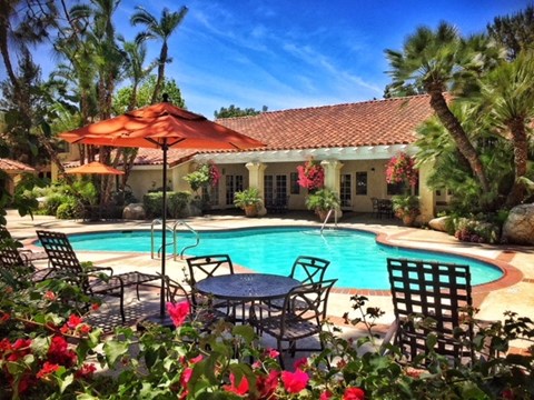 a swimming pool in front of a house with a pool table and umbrella