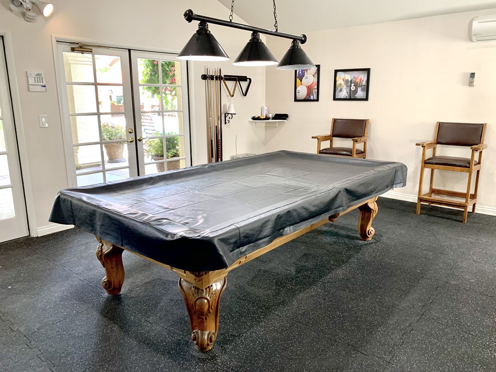 a pool table with a black cloth on it in a room with two chairs and at Victoria Springs, Riverside California