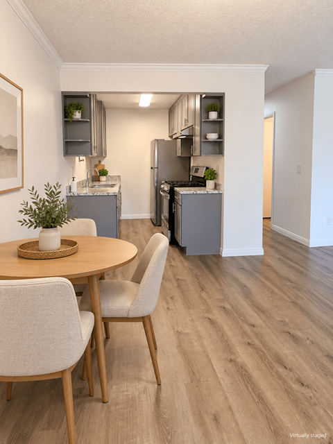 A kitchen with a table and chairs in the foreground and a refrigerator in the background.