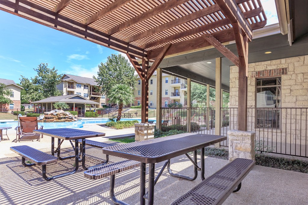 our apartments have a patio with picnic tables and a pool at The Villages at Lost Creek, San Antonio, TX 78247