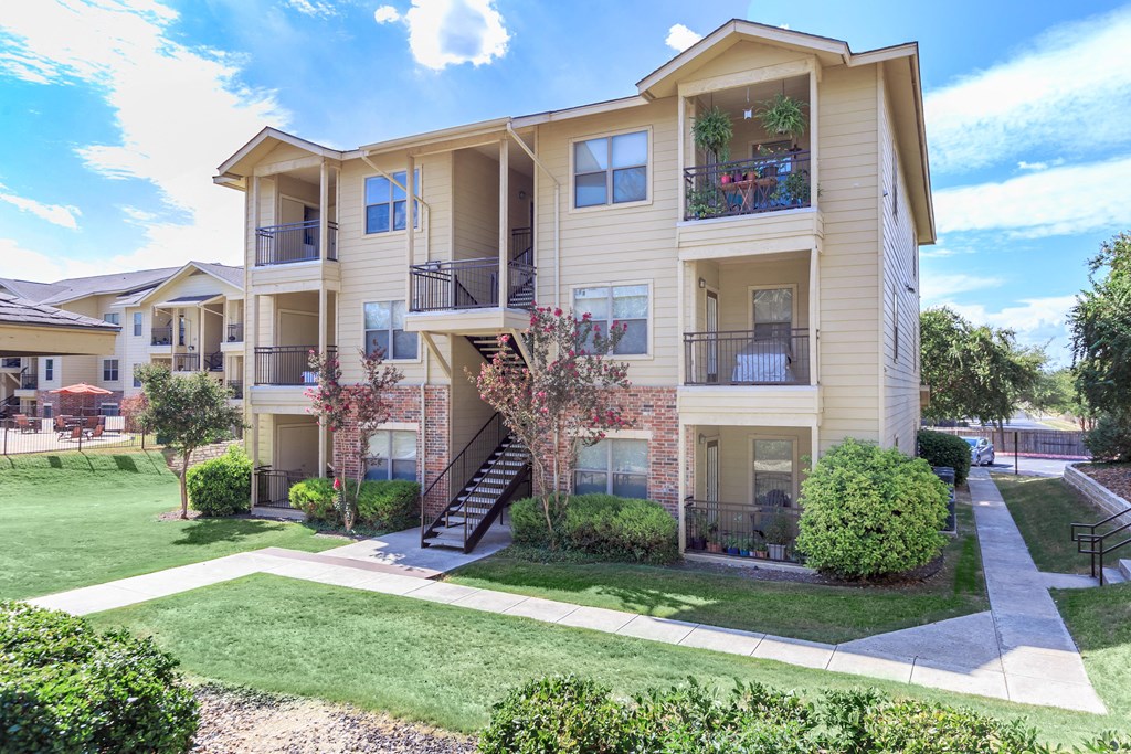 the outlook of an apartment building with lawns and trees at The Villages at Lost Creek, Texas