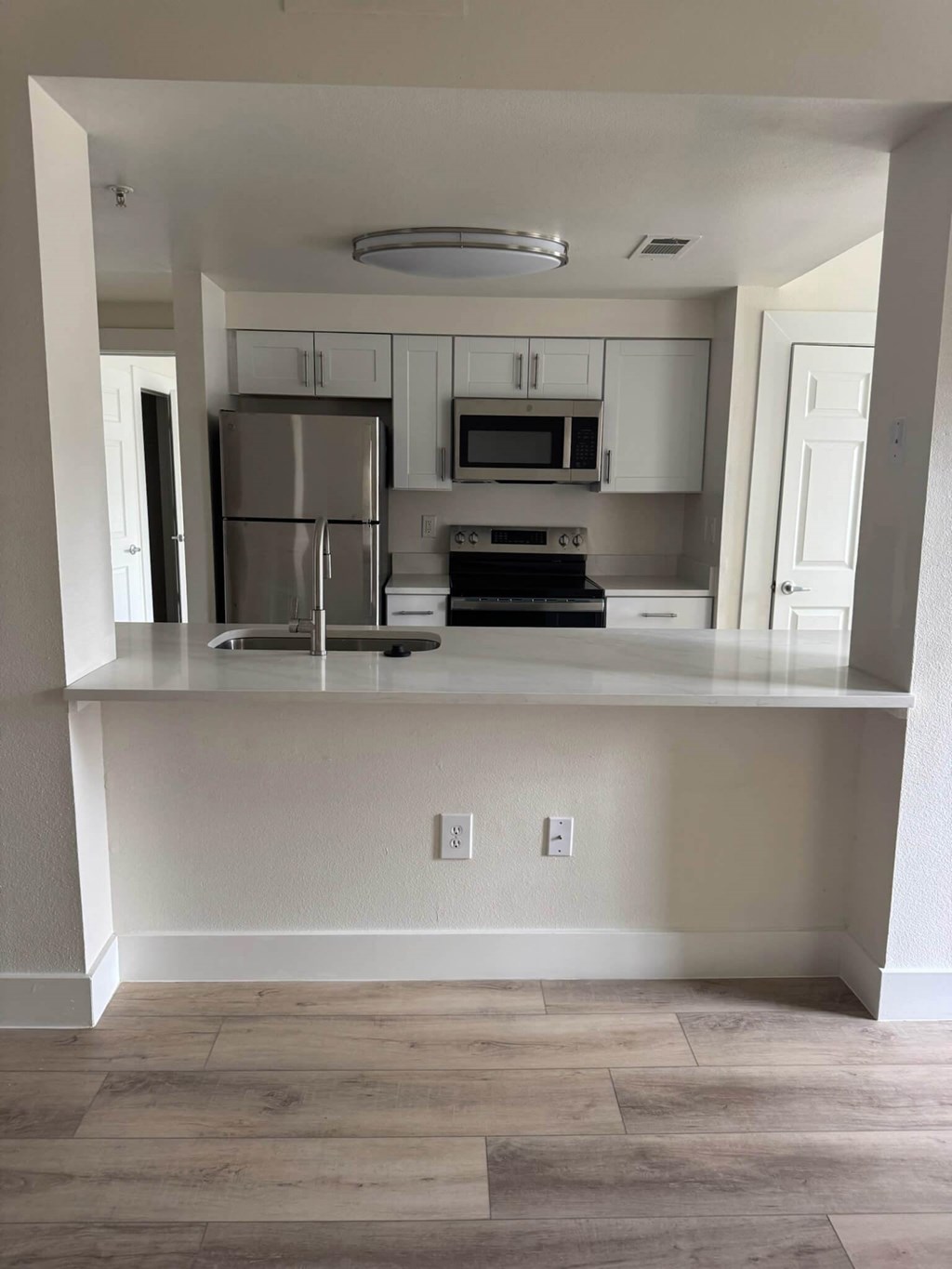 A kitchen with white cabinets and a stainless steel refrigerator.