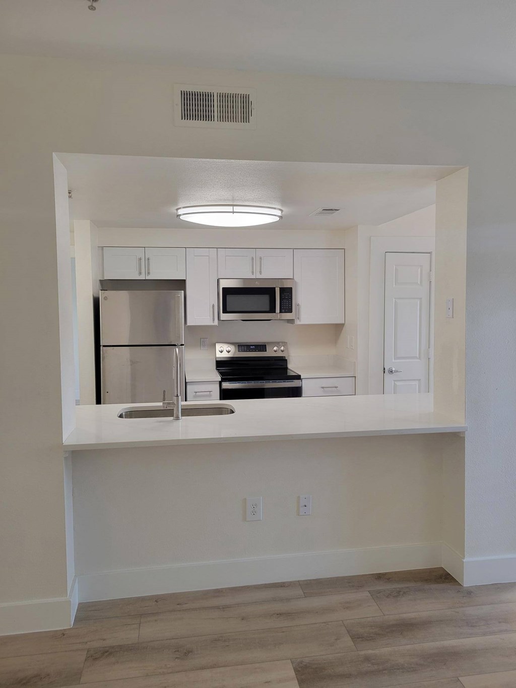 A kitchen with white cabinets and a stainless steel refrigerator.