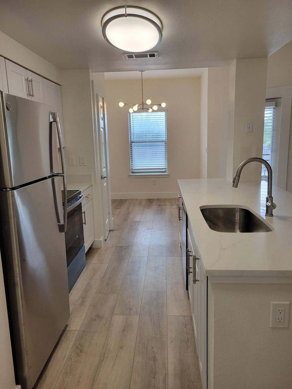 A kitchen with a stainless steel refrigerator and a sink.