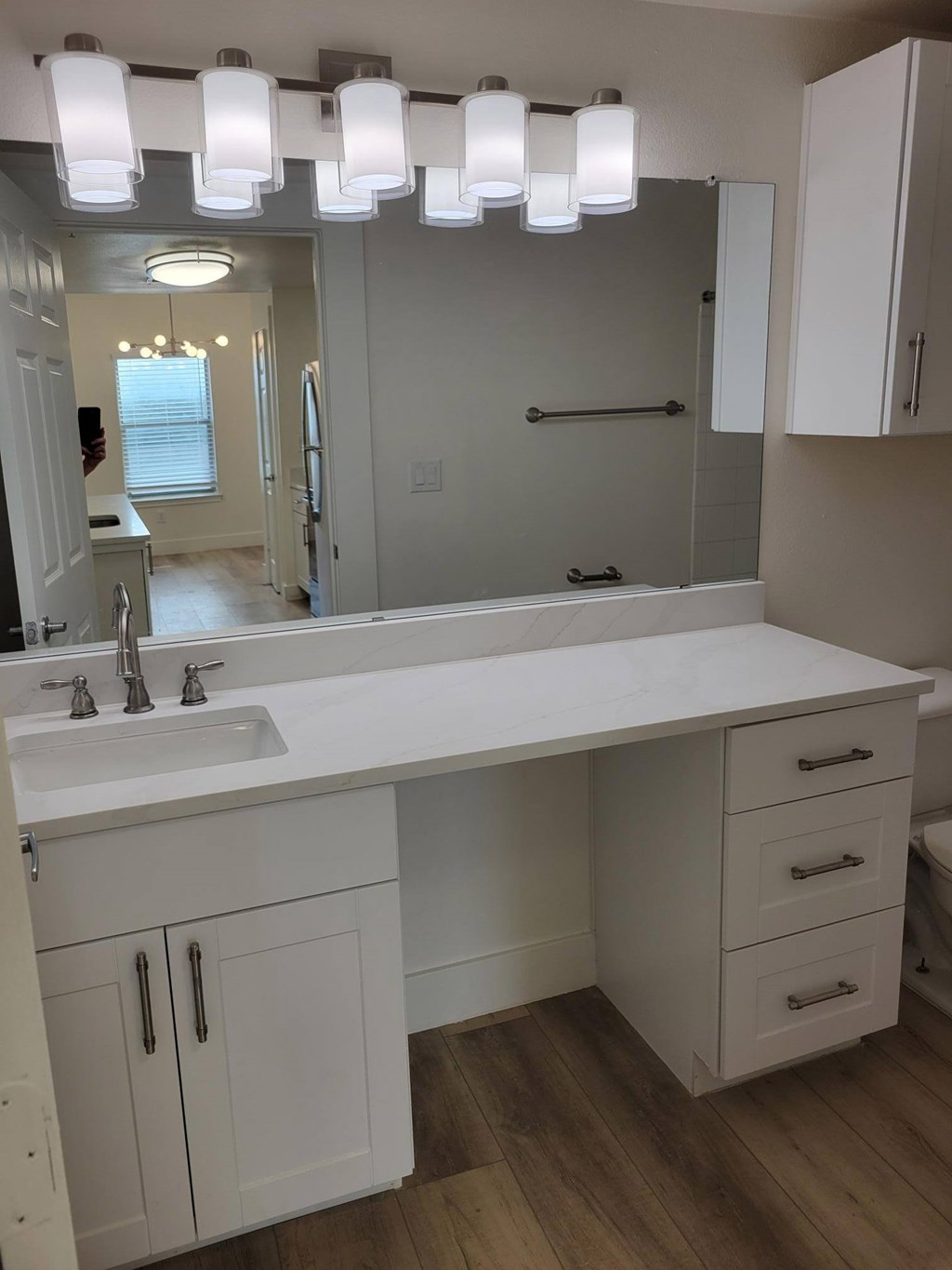 A bathroom with a white counter top and a mirror above it.