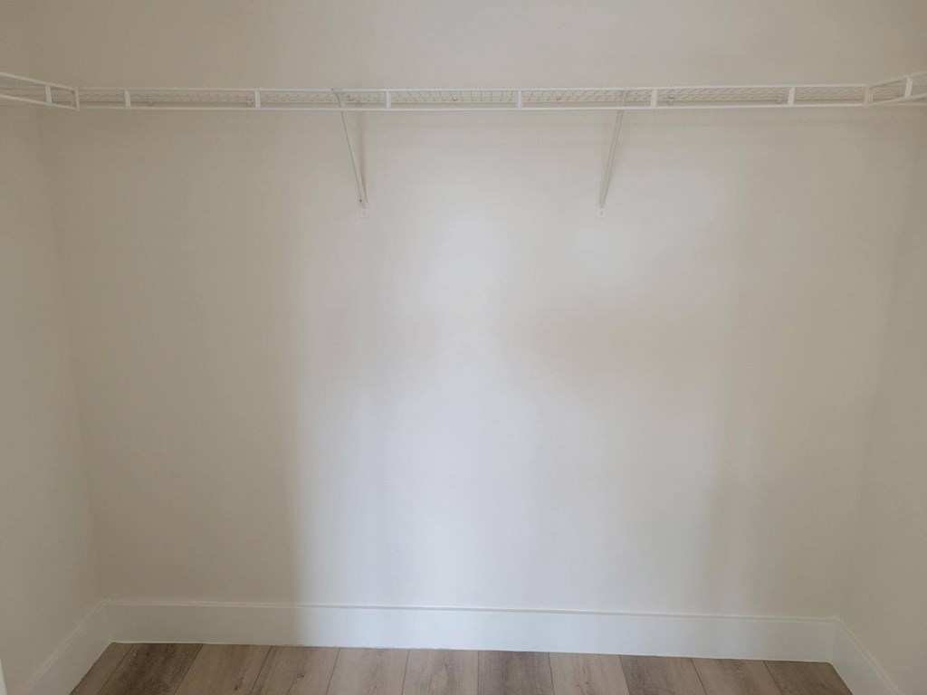 A white wall with a white shelf and a white floor.