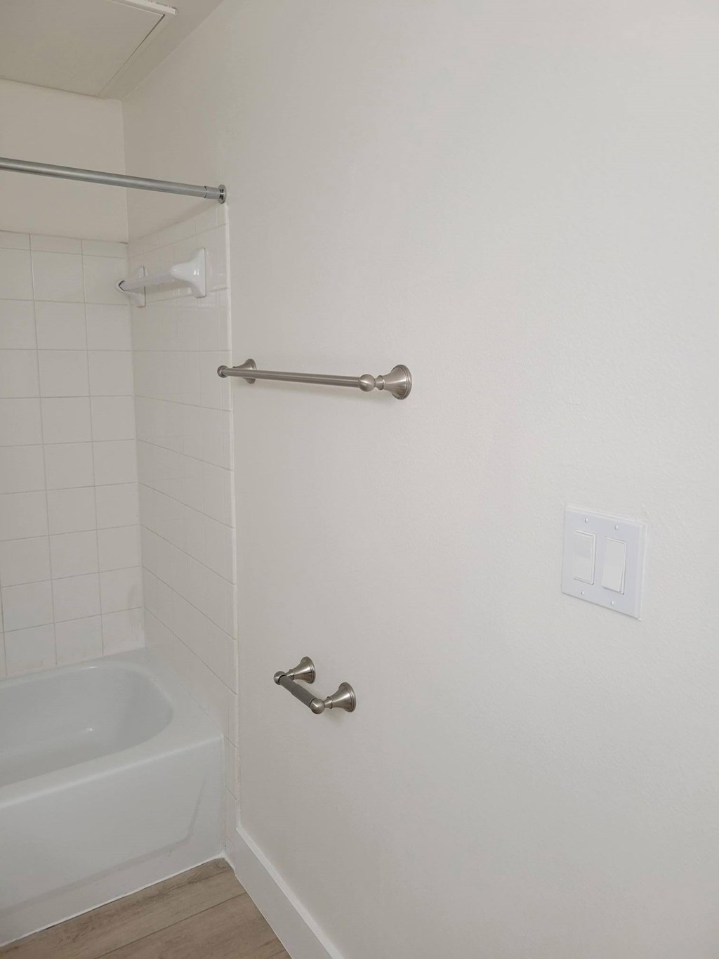 A white bathroom with a tub and a towel rack.