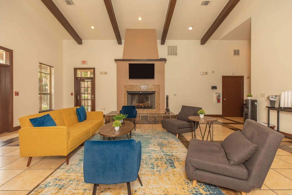 A living room with a yellow couch, blue chair, and a fireplace at The Villages at Lost Creek Apartments, San Antonio