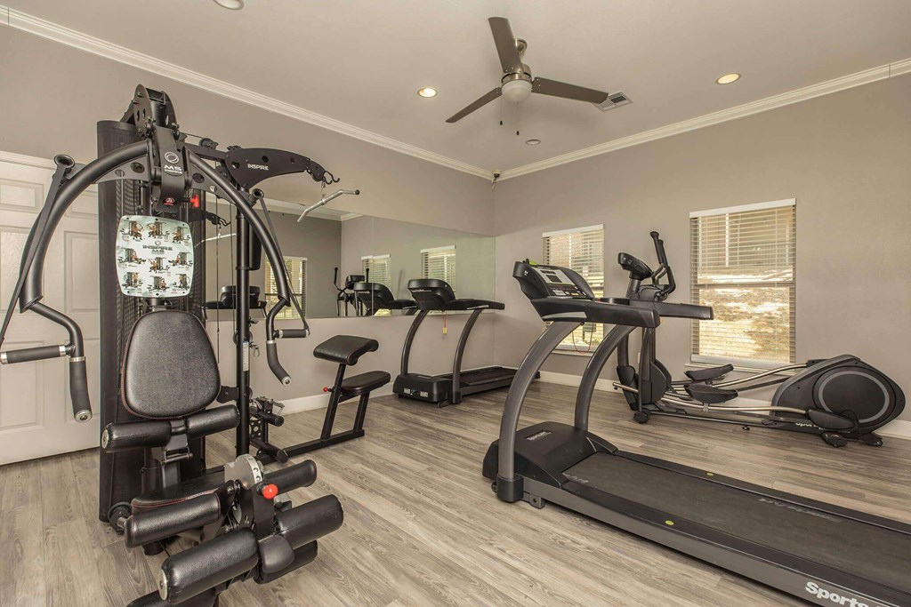 A spacious home gym with a variety of exercise equipment at The Villages at Lost Creek Apartments, Texas