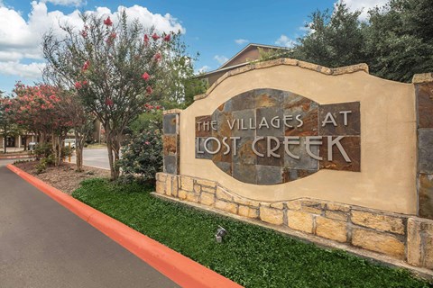 The Villages at Lost Creek entrance sign with a tree in the background.