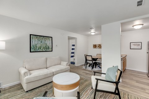 A living room with a white couch and a painting on the wall.