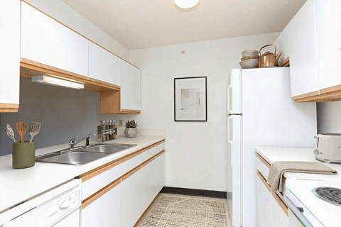 A kitchen with white cabinets and a fridge.