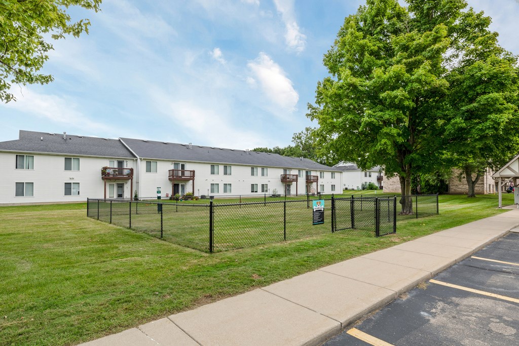 A row of white houses with green trees in front.
