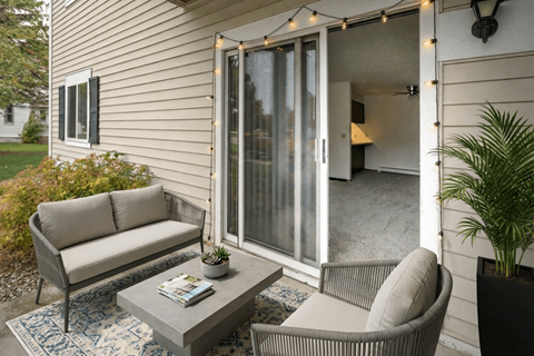 A patio with a grey sofa, a grey coffee table, and a chair with a plant on the side.