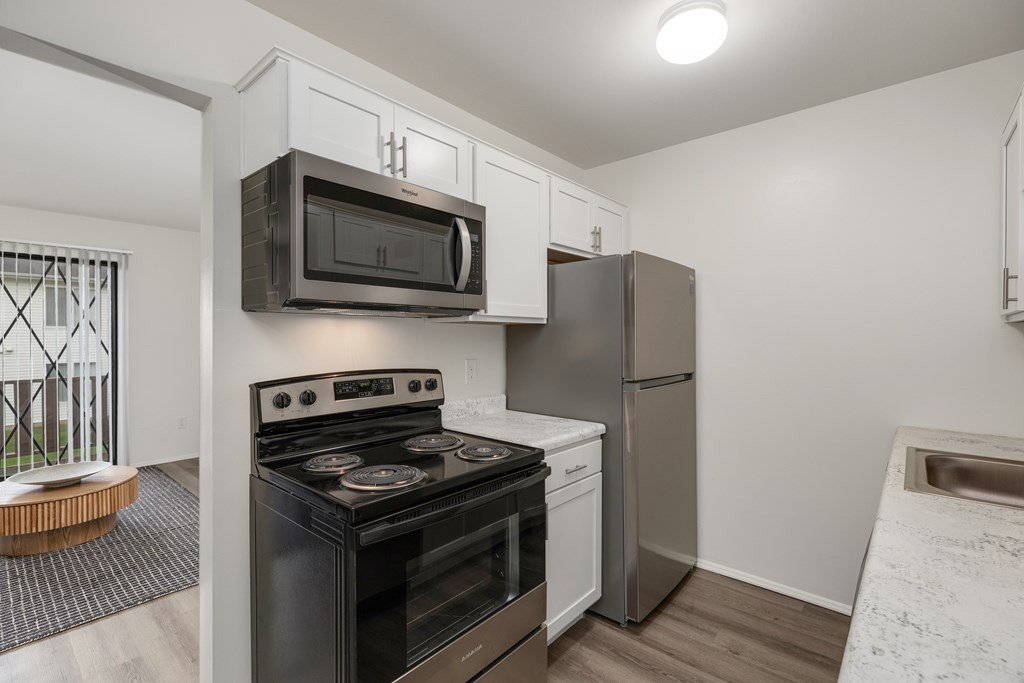 A kitchen with a black stove top oven, a black microwave, and a silver refrigerator.