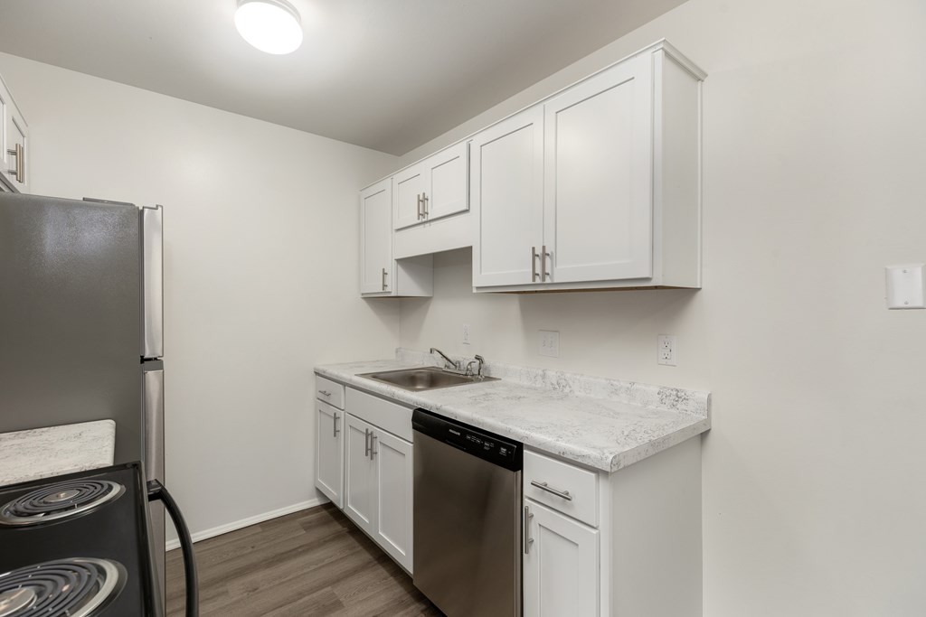 A kitchen with white cabinets and a black refrigerator.