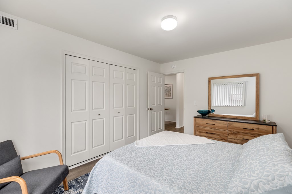 A bedroom with a bed, chair, and wardrobe.