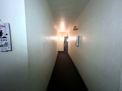 A hallway with a sign on the wall and a door at the end.