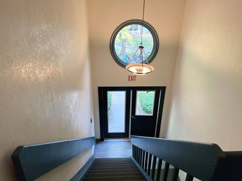 A hallway with a round window and a hanging light fixture.