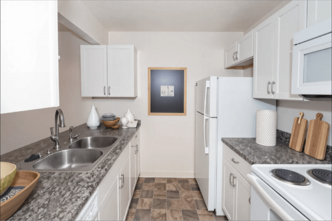 A kitchen with white cabinets and a fridge.