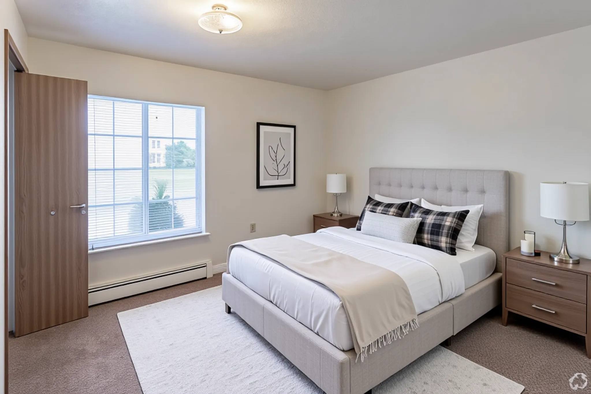 A bedroom with a large bed, nightstand, and window.
