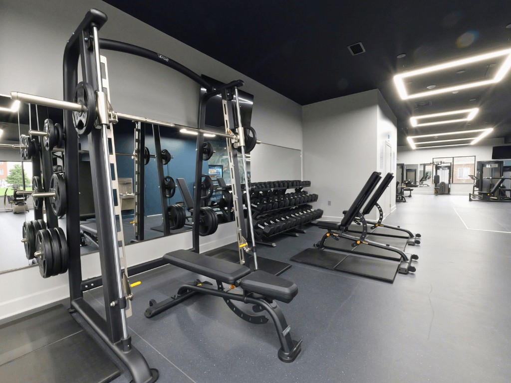 A gym with a variety of equipment including weightlifting machines and benches.